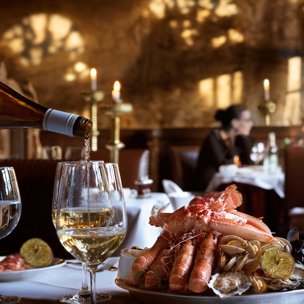 Elegant dining room at The Witchery with candlelit tables set with fine wine glasses and gourmet dishes.