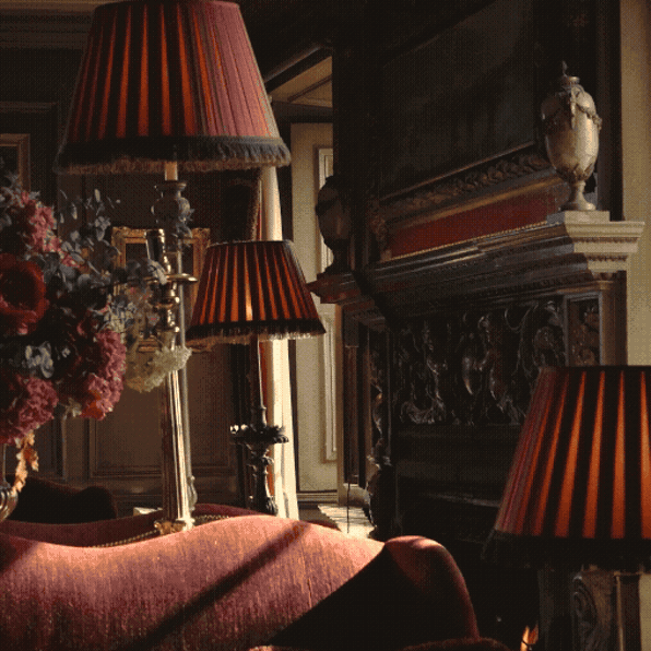 Animated image switching between antique velvet lamp shades on a table beside an grand ornate carved fireplace, logs burning in a fireplace, wine glasses and champagne flutes at Prestonfield luxury Edinburgh hotel