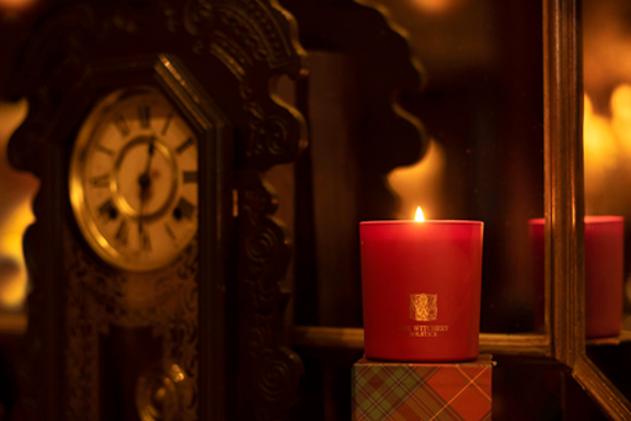 The Witchery candle on a fireplace by an antique clock